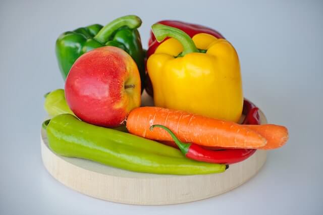 circular wood cutting board displaying colorful fruits and vegetables