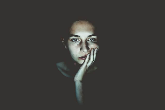 young woman in somber mood in the dark for article about the serious impacts of alcohol on the nervous system